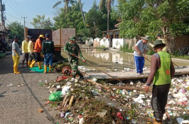 Babinsa Koramil Tirtayasa Bersama Petugas DLH Bersinergi Bersihkan Sampah Di Saluran Irigasi